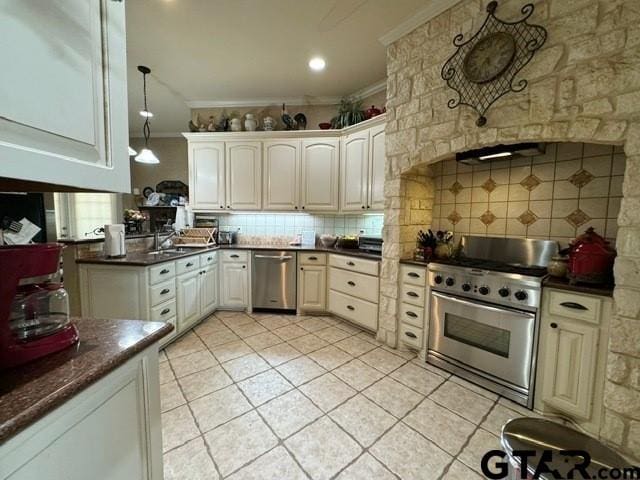 kitchen featuring stainless steel appliances, dark countertops, ornamental molding, light tile patterned floors, and decorative backsplash
