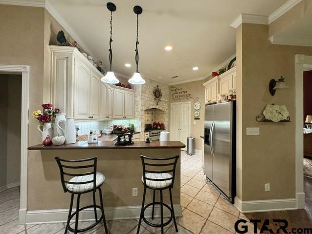 kitchen with a peninsula, dark countertops, a kitchen bar, and stainless steel appliances
