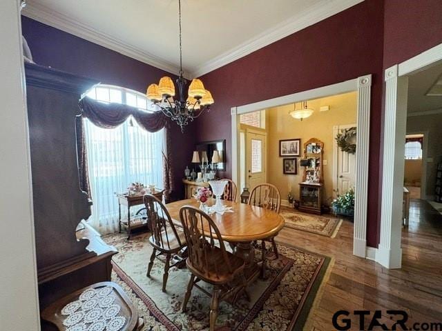 dining area featuring wood finished floors, a notable chandelier, and ornamental molding
