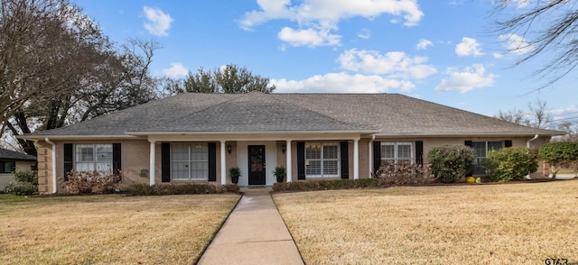 ranch-style home with a front lawn, roof with shingles, and brick siding