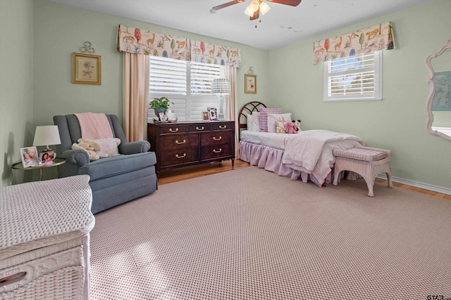 bedroom featuring a ceiling fan, multiple windows, baseboards, and wood finished floors