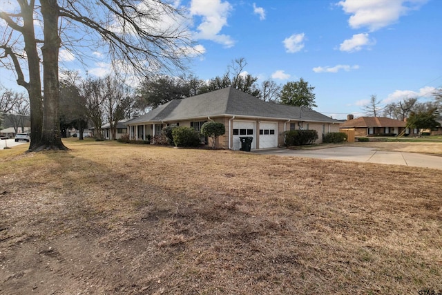 view of side of property with concrete driveway, a yard, roof with shingles, and an attached garage