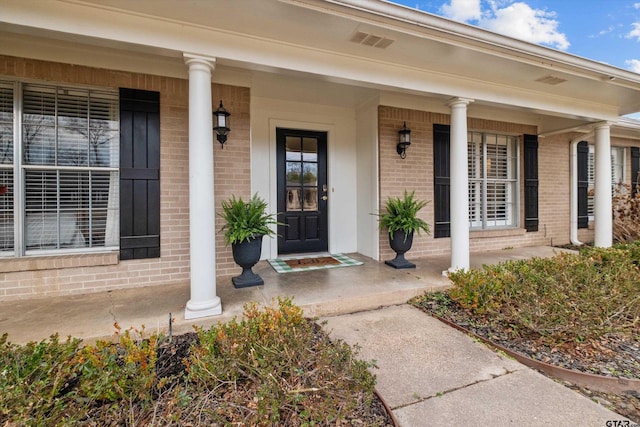 doorway to property with covered porch and brick siding