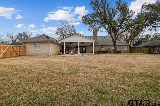 rear view of property with a patio, brick siding, fence, a ceiling fan, and a yard