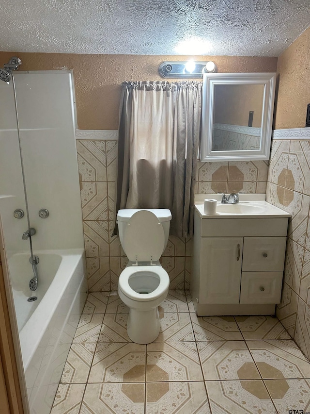 full bathroom featuring tile walls, vanity, a textured ceiling,  shower combination, and toilet