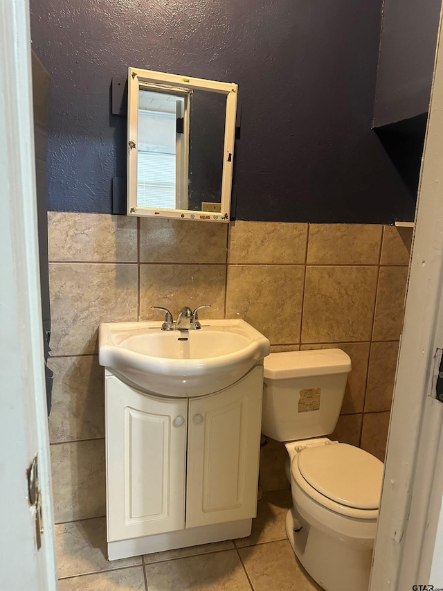 bathroom featuring tile patterned floors, vanity, toilet, and tile walls