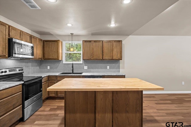 kitchen featuring wooden counters, dark wood-type flooring, sink, a kitchen island, and appliances with stainless steel finishes