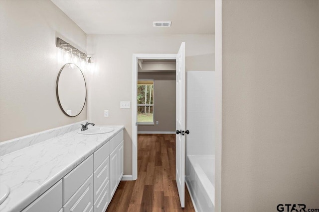 bathroom with a bathing tub, vanity, and hardwood / wood-style flooring