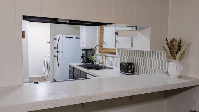 1418 E Dawson St, Tyler, TX 75701 - kitchen with washer and clothes dryer, freestanding refrigerator, white cabinets, and backsplash