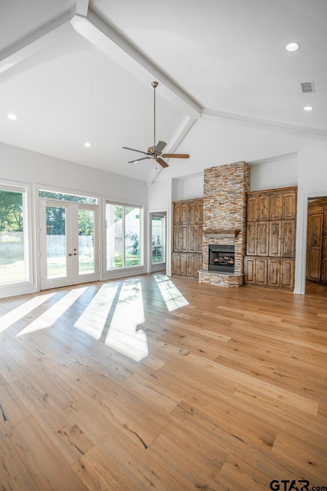 unfurnished living room with a stone fireplace, high vaulted ceiling, light hardwood / wood-style floors, beamed ceiling, and ceiling fan