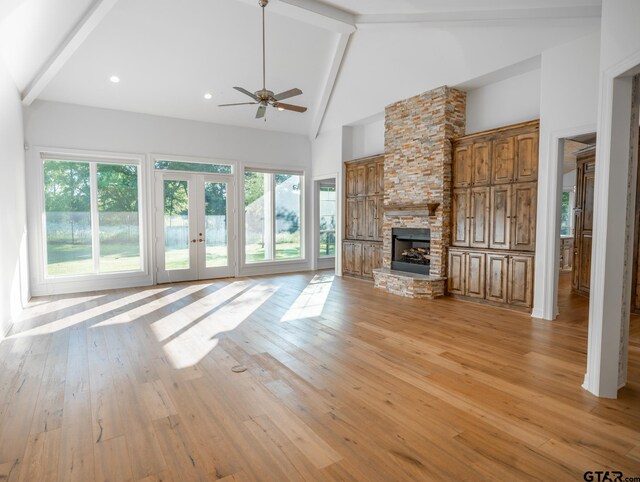 unfurnished living room with a fireplace, high vaulted ceiling, beamed ceiling, ceiling fan, and light hardwood / wood-style flooring