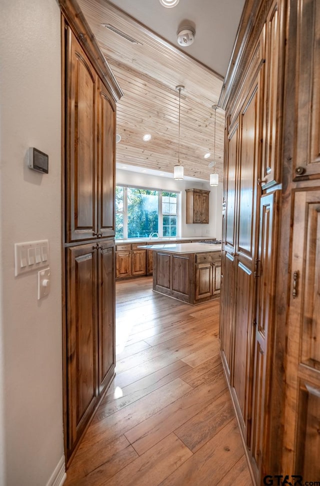 kitchen with decorative light fixtures, light hardwood / wood-style floors, and a center island