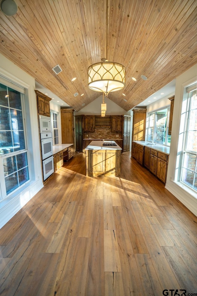 kitchen with plenty of natural light, decorative light fixtures, a center island, and white appliances