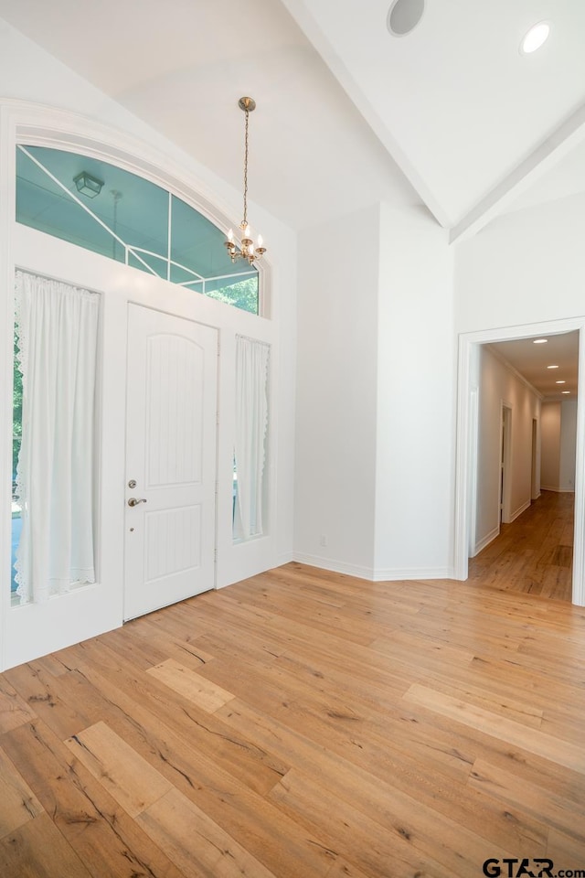 entrance foyer with hardwood / wood-style floors, a notable chandelier, and lofted ceiling