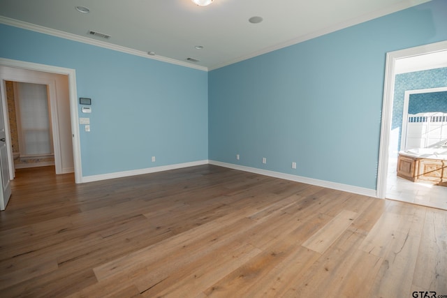 spare room with light wood-type flooring and crown molding