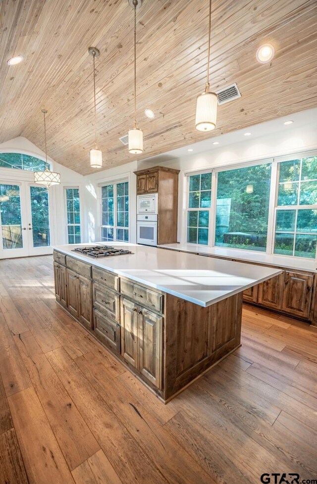 kitchen with pendant lighting, plenty of natural light, lofted ceiling, and a kitchen island