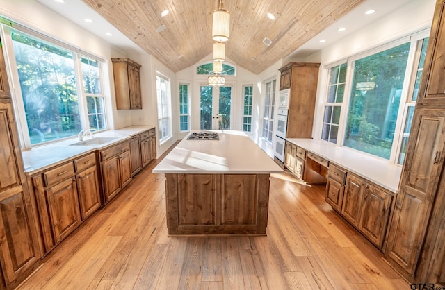 kitchen featuring light hardwood / wood-style floors, lofted ceiling, decorative light fixtures, and a healthy amount of sunlight