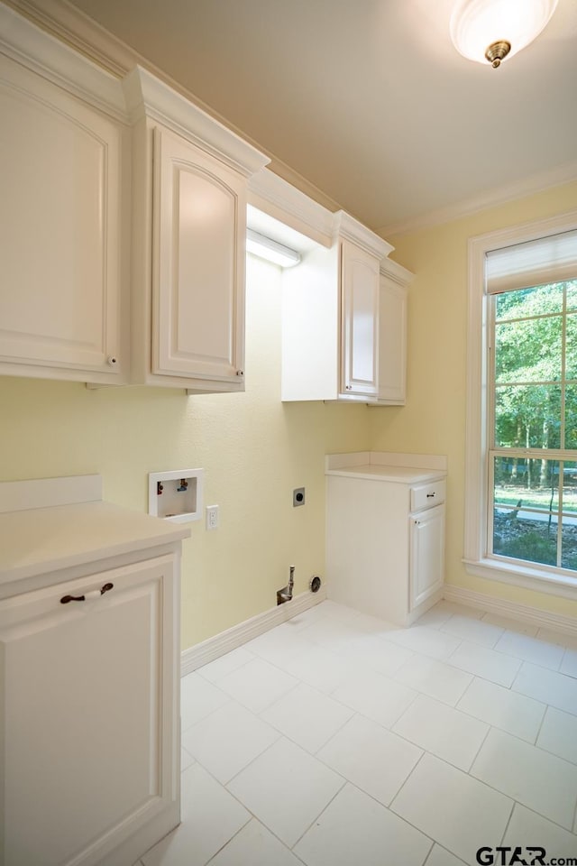 laundry area with ornamental molding, hookup for an electric dryer, hookup for a washing machine, light tile patterned floors, and cabinets