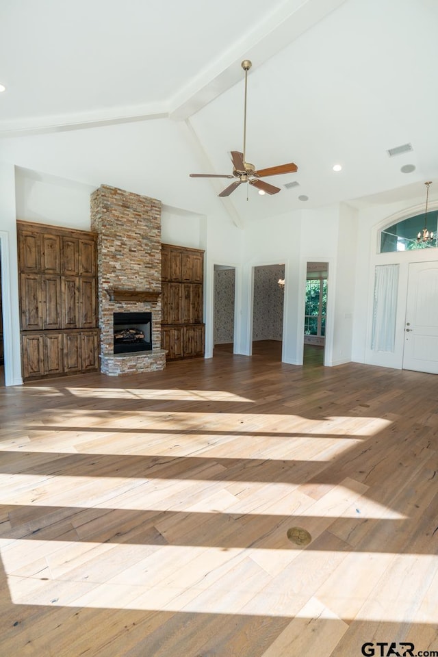 unfurnished living room featuring light hardwood / wood-style floors, beamed ceiling, ceiling fan, high vaulted ceiling, and a fireplace