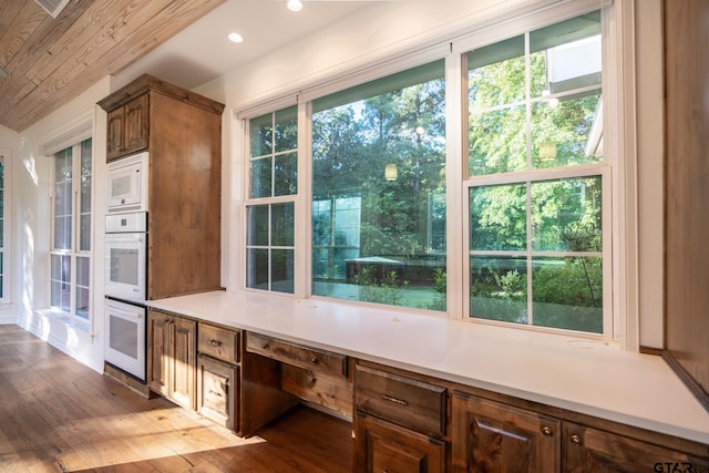 kitchen featuring built in desk, white microwave, and dark hardwood / wood-style floors