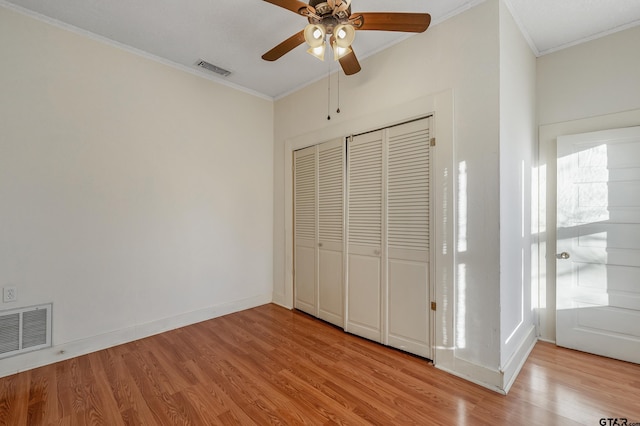 unfurnished bedroom with crown molding, a closet, ceiling fan, and light hardwood / wood-style flooring