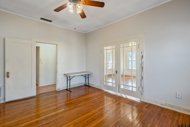 empty room featuring ornamental molding, hardwood / wood-style floors, ceiling fan, and french doors