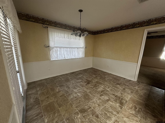 unfurnished dining area featuring a notable chandelier, wainscoting, and visible vents