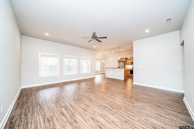 unfurnished living room featuring ceiling fan and dark hardwood / wood-style flooring