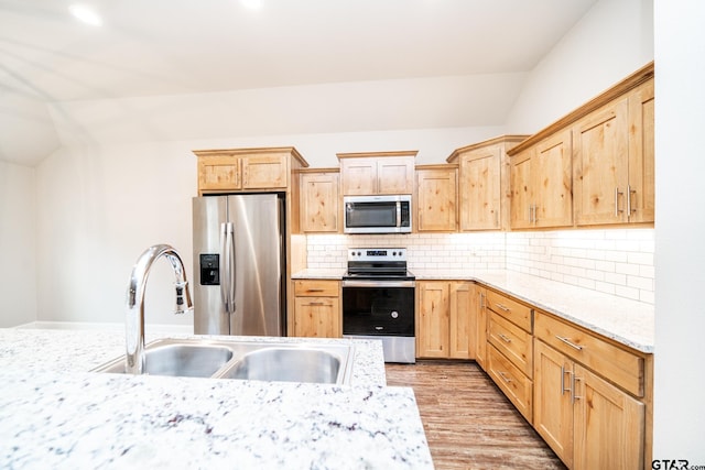 kitchen featuring light brown cabinets, backsplash, light wood-type flooring, appliances with stainless steel finishes, and light stone counters