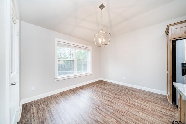 spare room with hardwood / wood-style floors and a chandelier