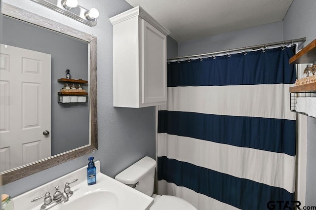 bathroom with a shower with shower curtain, toilet, and sink