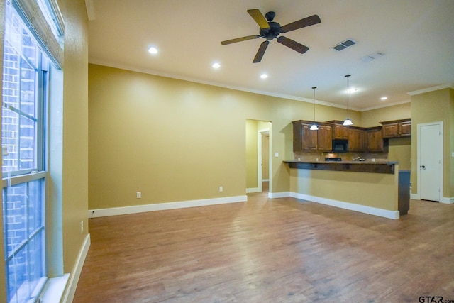 kitchen featuring hardwood / wood-style floors, a healthy amount of sunlight, decorative light fixtures, and kitchen peninsula