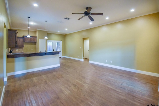 kitchen featuring hanging light fixtures, hardwood / wood-style flooring, crown molding, and ceiling fan