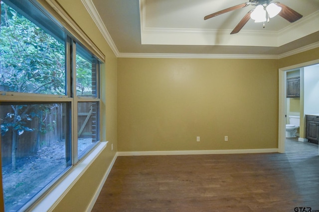 spare room with a raised ceiling, dark wood-type flooring, ceiling fan, and crown molding