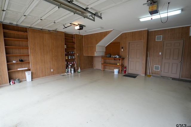 garage with a garage door opener and wood walls