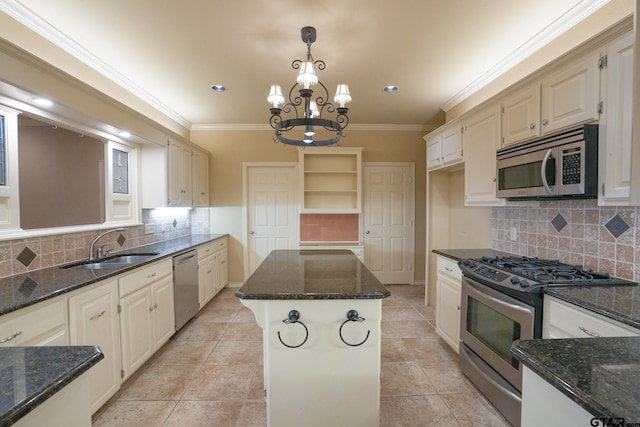 kitchen with appliances with stainless steel finishes, a center island, hanging light fixtures, and dark stone countertops