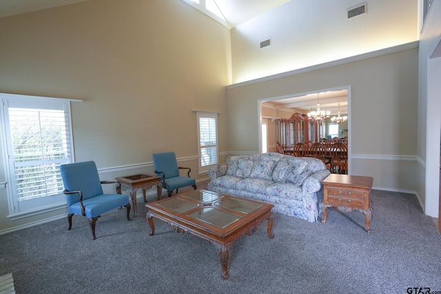 carpeted living room featuring a towering ceiling and a notable chandelier