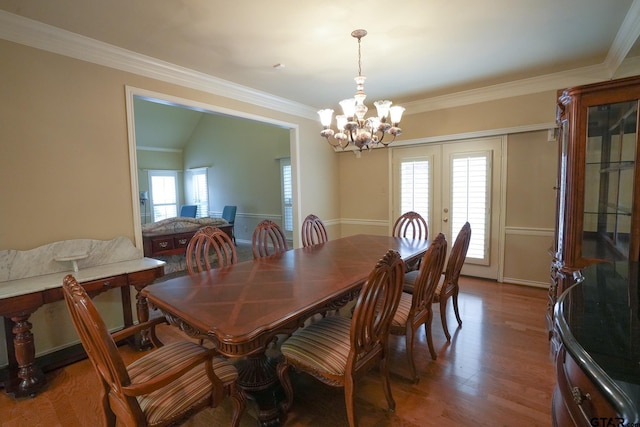 dining room featuring french doors, lofted ceiling, crown molding, a chandelier, and hardwood / wood-style flooring