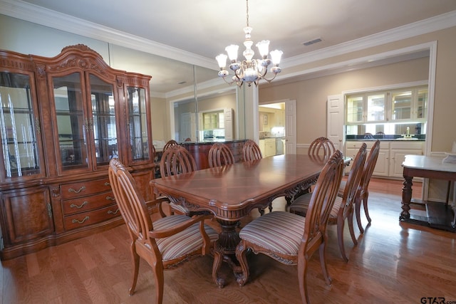 dining space featuring ornamental molding, an inviting chandelier, and light hardwood / wood-style flooring