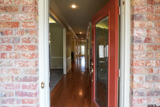 hall with ornamental molding, dark hardwood / wood-style floors, and brick wall