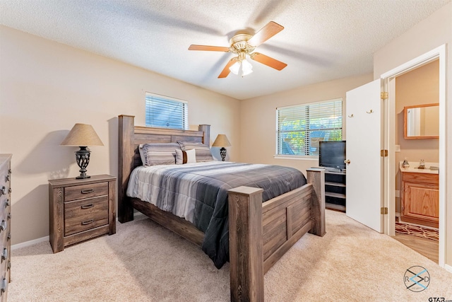 bedroom with a textured ceiling, light colored carpet, ceiling fan, and ensuite bath