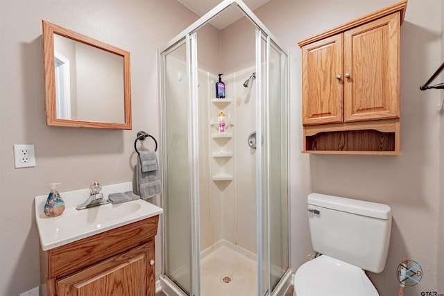 bathroom with toilet, vanity, and a shower with door