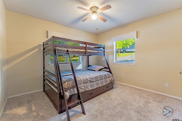 bedroom with ceiling fan, a textured ceiling, and light colored carpet