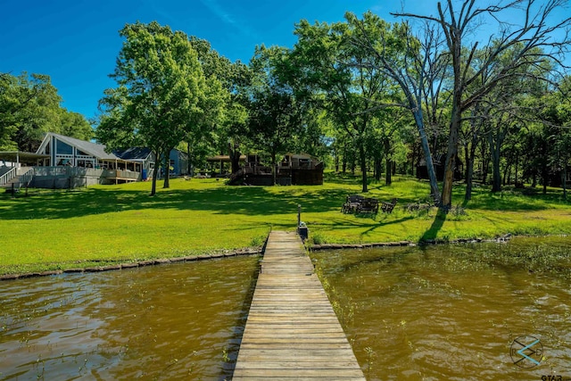 view of dock with a water view and a lawn