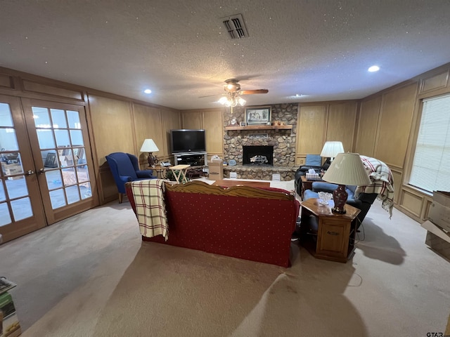 living room featuring ceiling fan, a fireplace, a textured ceiling, light carpet, and french doors