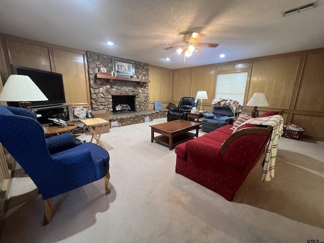 living room with ceiling fan, a fireplace, light carpet, and a textured ceiling