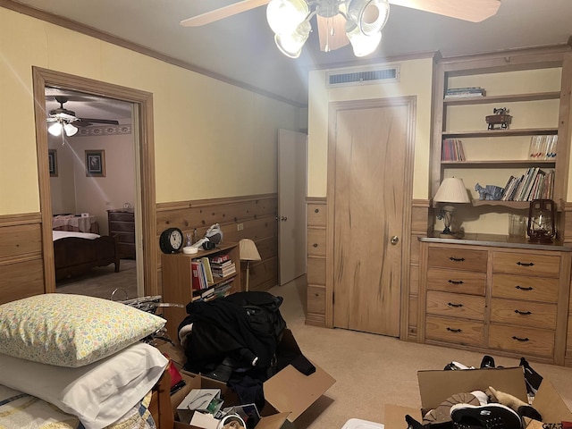 carpeted bedroom featuring crown molding, ceiling fan, and wood walls