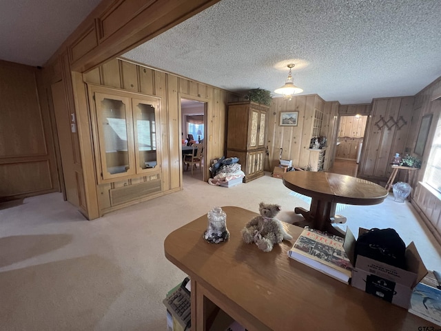 carpeted dining room featuring wooden walls and a textured ceiling