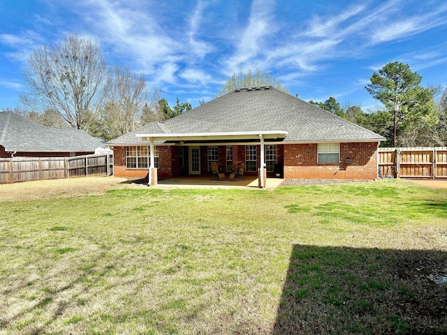 rear view of property featuring a patio, a fenced backyard, a shingled roof, a lawn, and brick siding