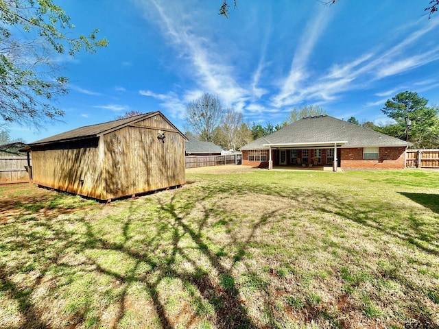 view of yard featuring a storage shed, an outdoor structure, a fenced backyard, and a patio area